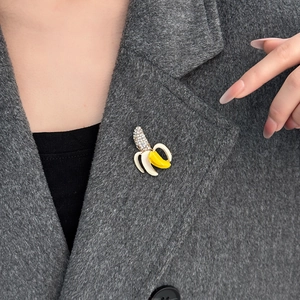 Broche banane créative avec émail jaune et cristaux brillants sur un manteau en laine gris
