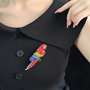 Broche perroquet colorée en strass portée sur un revers noir pour une mode haut de gamme