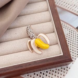Broche banane créative avec cristaux et émail jaune sur un plateau en bois