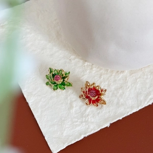 Close-up of green and red lotus flower brooches with gold plating on textured paper
