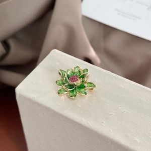 Macro shot of green lotus brooch with gold base and pink crystal heart detail