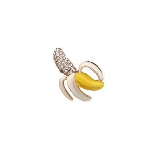 Broche banane chic en or avec émail et strass brillants sur un fond blanc épuré