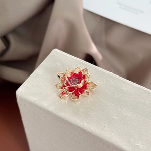 Detail of flower brooch with crimson petals, purple crystals, and gold metal frame