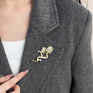 Élégante broche tulipe dorée avec pétales en opale et strass sur un blazer en tweed