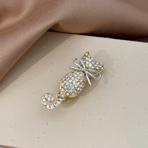 Close-up of cat brooch with sparkling rhinestones and silver bow on textured fabric