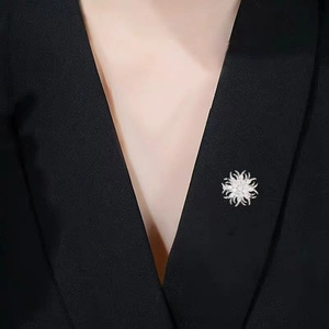 Nahaufnahme einer glitzernden Blumenbrosche mit Strasssteinen auf schwarzem Revers