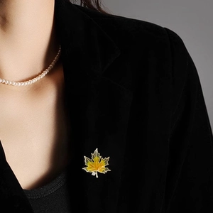 Detailed close-up of a vintage maple leaf brooch pinned on a black velvet blazer collar