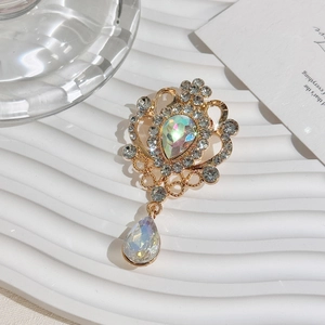Close-up of golden vintage crown brooch with sparkling AB crystal teardrop pendants