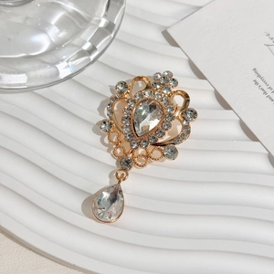 Close-up of golden vintage crystal brooch with teardrop rhinestone in elegant setting