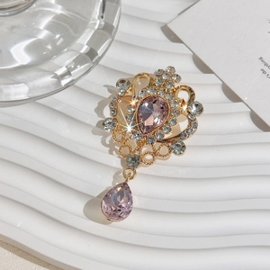 Close-up of golden vintage crystal brooch with teardrop rhinestones on white display