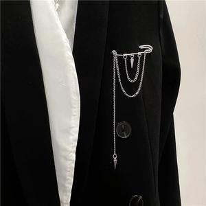 Unisex silver punk safety pin brooch with hanging chains and metallic spikes on suit