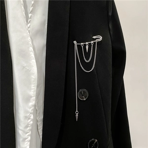 Detail of silver safety pin brooch with hanging chains and cone pendants on black blazer