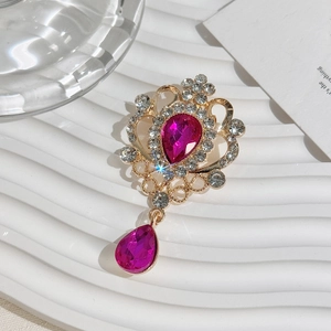 Detail shot of vintage golden crown brooch with pink teardrop gemstones and small rhinestones