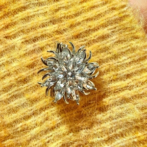 Eleganter Blumen-Brosche aus Silber mit Zirkonia auf gelbem Strickhintergrund