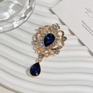 Detailed macro view of vintage gold flower brooch with navy blue teardrop pendants