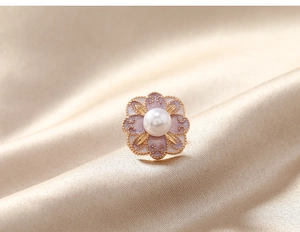 Détail d'une broche fleur vintage en émail violet avec perle sur fond de soie