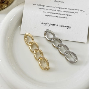 Gold and silver polished chain brooches on a white ceramic plate with a card