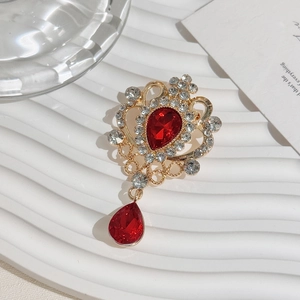 Macro detail of golden crown brooch with red teardrop gemstones and clear rhinestones