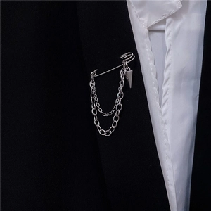 Silver safety pin brooch with double metal chains and geometric charms on black blazer