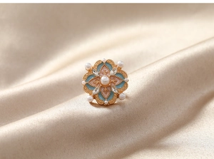 Gros plan sur la broche fleur vintage avec émail bleu, perles et cristaux marquise