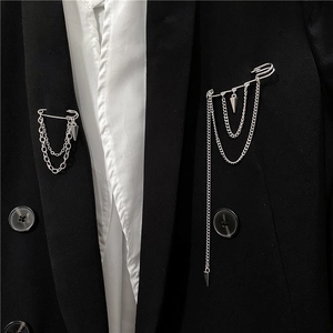 Detail of silver safety pin brooches with hanging chains on a black suit lapel