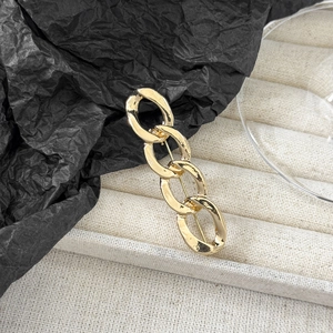 Macro shot of polished gold chain brooch pins on a beige velvet jewelry display box