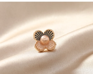 Détail d'une épingle fleur vintage avec émail noir et perle rose sur de la soie
