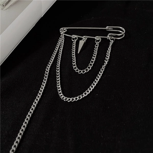 Macro shot of silver punk safety pin brooch with hanging metal chains and cone pendant