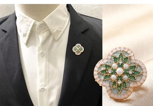 Détail macro de broche vintage florale avec émail vert, perles et cristaux
