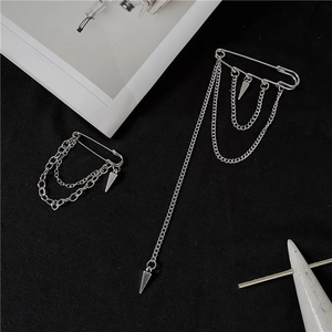 Detail view of silver safety pin earrings with dangling chains and punk style cone pendants
