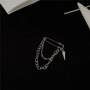 Silver safety pin brooch with double chains and cone pendant on a black background