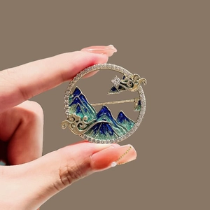 Détail d'une broche ronde paysage chinois avec émail montagne et bordure zircon