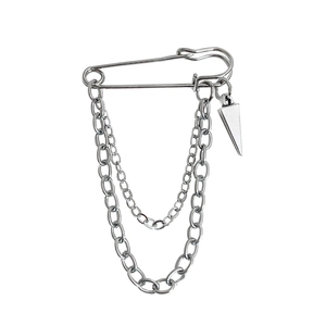 Close-up of silver punk style safety pin brooch with hanging chains and triangle pendant