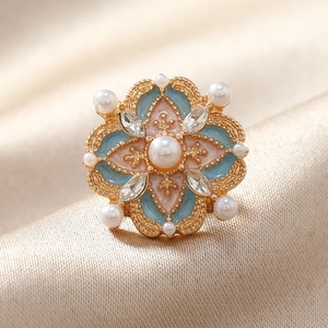 Broche fleur vintage en métal doré avec émail et perles sur fond en soie chic