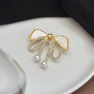Vue détaillée d'une élégante broche nœud avec cristaux et pendentifs en perles
