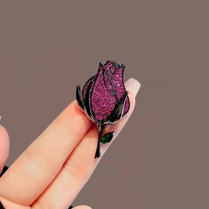 Elegant rose bud brooch with pink pavé crystals and green leaf on black plated metal