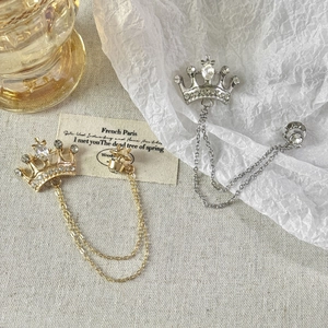 Macro shot of gold and silver crown brooches with tassels and inlaid rhinestones