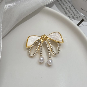 Vue macro de la broche nœud avec nacre, strass et gouttes de perles élégantes