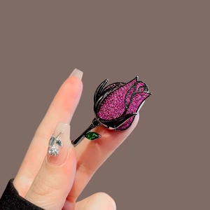 Detailed close-up of a vintage rose brooch with pink crystals and a green gem leaf