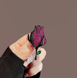 Detailed view of luxury rose brooch with pink crystals and black metal leaf