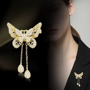 Detailed view of golden butterfly brooch with hollow wings and pearl tassel pendants