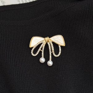 Détail macro de l'élégante broche nœud dorée avec cristaux brillants et perles blanches