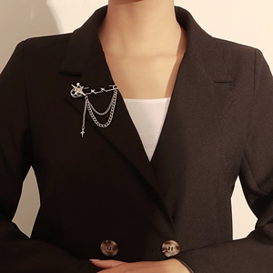 Detail of star and Saturn pendant brooch with layered metal chains on a black blazer lapel