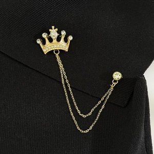 Close-up of gold crown brooch with sparkling rhinestones and elegant hanging chains