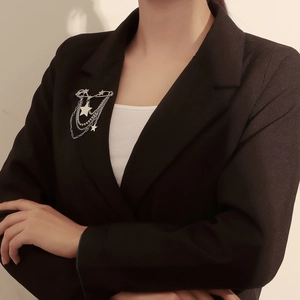 Detail of silver layered tassel brooch with star charms on a black suit lapel