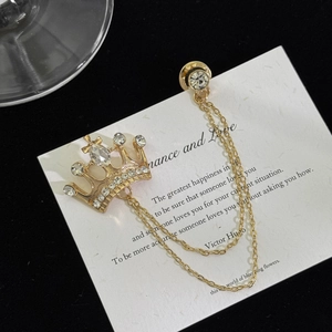 Macro detail of golden crown brooch with white rhinestones and double hanging chains