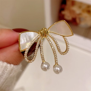 Broche nœud élégante en or avec nacre, zircons et deux pendentifs en perles blanches