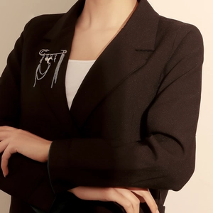 Close-up of silver multi-chain brooch with moon and cross charms on black blazer