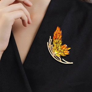 Broche papillon élégante avec cristaux orange dégradés sur une base en métal doré