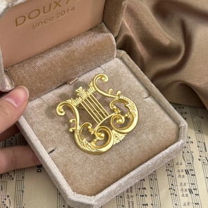 Vintage matte gold lyre harp brooch with classic scrollwork in a luxury velvet jewelry box